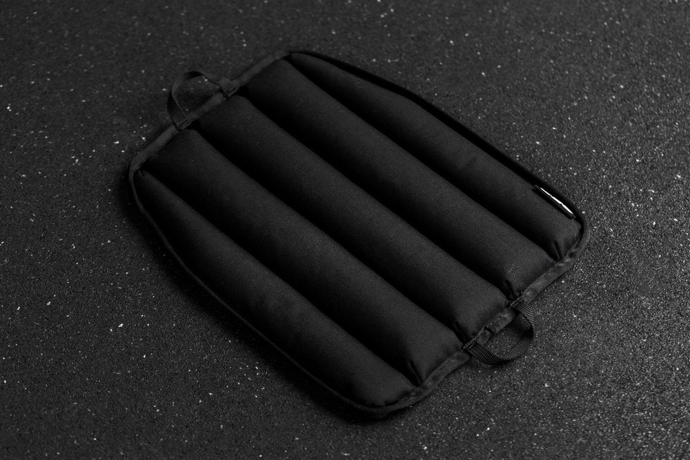 Black soft weight vest plate with ribbed texture on a dark textured background