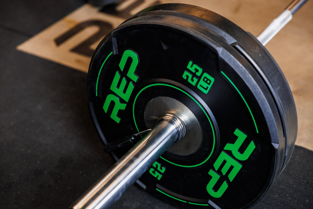 Close-up: A 25 lb REP Sport Bumper Plate 2.0 interlocks seamlessly with a 45 lb plate on the sleeve of a barbell.