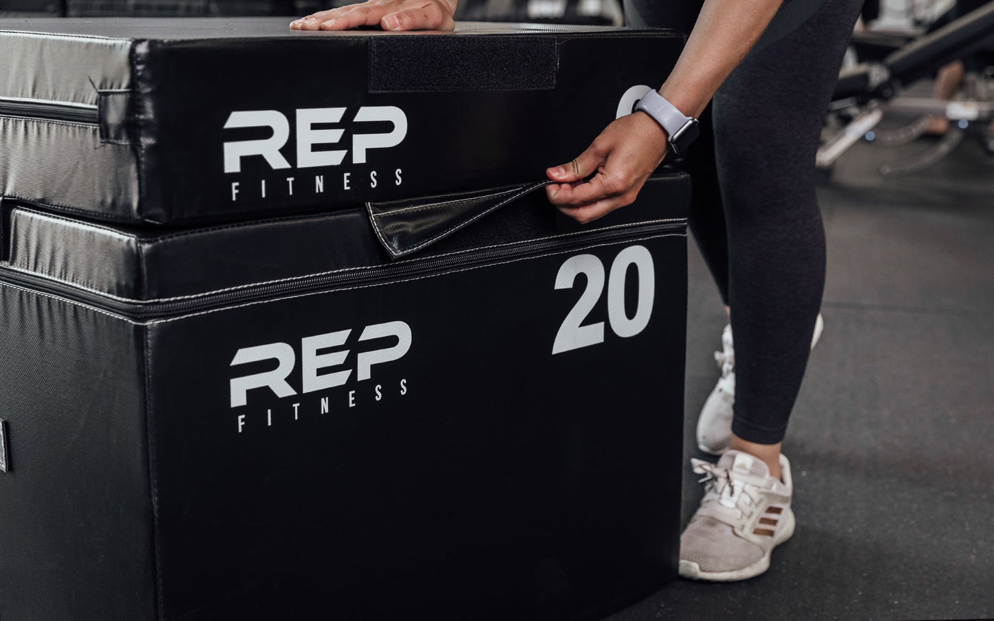 Female athlete securing the 6" REP Stackable Soft Plyo Box to the 20' via the 10" Velcro strap from Rep Fitness UK | Shop Best Premium Gym Equipment for Home & Commercial Use Online