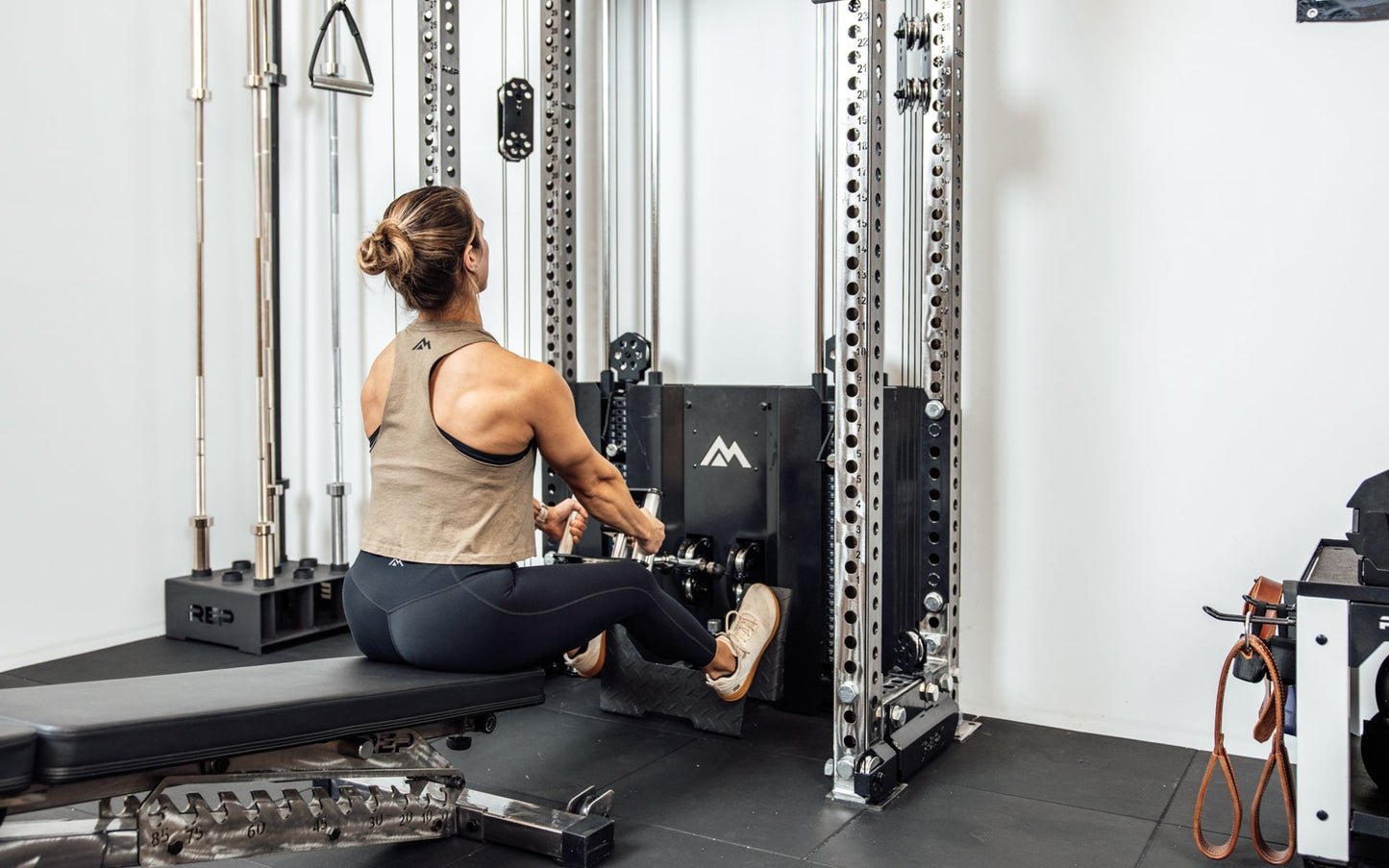 An athlete performing a low cable row on the Wall-Mounted Ares™ 2.0 while seated on a REP BlackWing™ bench