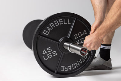 Lifter putting a spring clip onto a barbell loaded with 45lb Old School Iron Plates from Rep Fitness UK | Shop Best Premium Gym Equipment for Home & Commercial Use Online