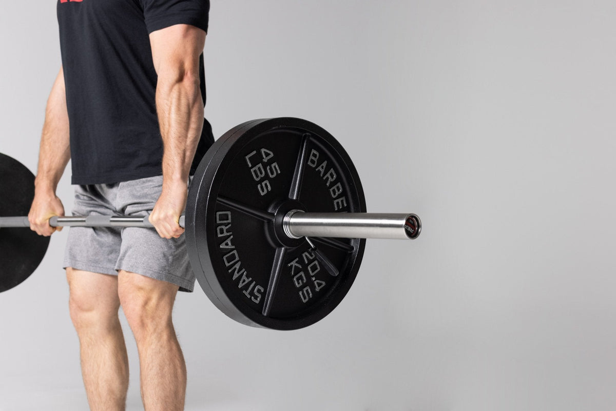Lifter at the top position of a deadlift using a barbell loaded with two pairs of 45lb Old School Iron Plates and spring clips. from Rep Fitness UK | Shop Best Premium Gym Equipment for Home & Commercial Use Online