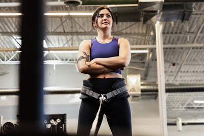 Woman in a gym wearing a sports bra and leggings with a weightlifting belt squat belt on from Rep Fitness UK | Shop Best Premium Gym Equipment for Home & Commercial Use Online
