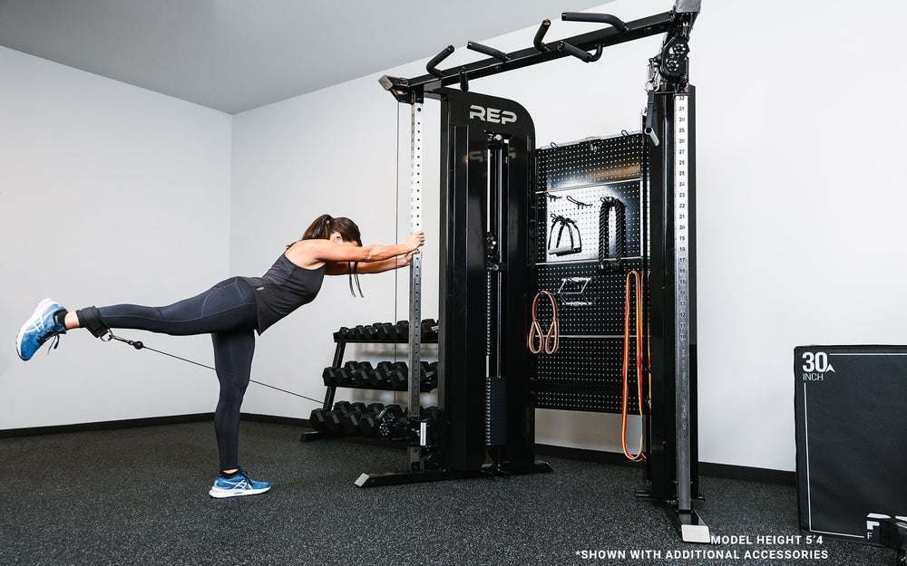 Woman doing leg extension strengthening exercises using pulley on Arcadia™ max stand-alone functional trainer, premium full-sized cable machine with grips hanging on the back board from Rep Fitness UK | Shop Premium Gym Equipment for Home & Commercial Use Online.