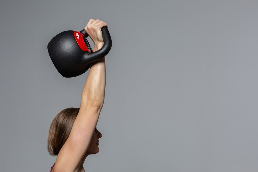 Woman exercising with the adjustable kettlebell from Rep Fitness UK, quick weight adjustment, non-slip matte powder coat, rubber base, and versatile for home gyms| Shop Premium Gym Equipment for Home & Commercial Use, Best Online Gym Equipment UK