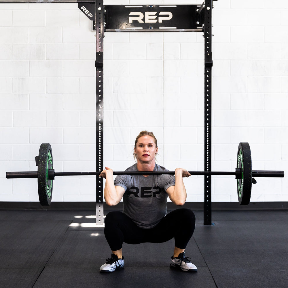 Woman using 15 kg Colorado Bar weightlifting bar in squat position ideal for strength training and gym workouts from Rep Fitness UK | Shop Premium Gym Equipment for Home & Commercial Use Online| Best Online Gym Equipment UK