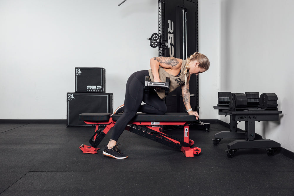 Woman using Nighthawk bench for crunches compact, high-performance bench for home and light-commercial gyms; 7- and 14-gauge steel frame, 7 back and 4 seat positions, CleanGrip™ vinyl pad, knurled handle, heavy-duty wheels, IPF-compliant 16.7” height, vertical storage, and compatibility with leg curl and roller attachments from Rep Fitness UK | Shop Best Premium Gym Equipment for Home & Commercial Use Online