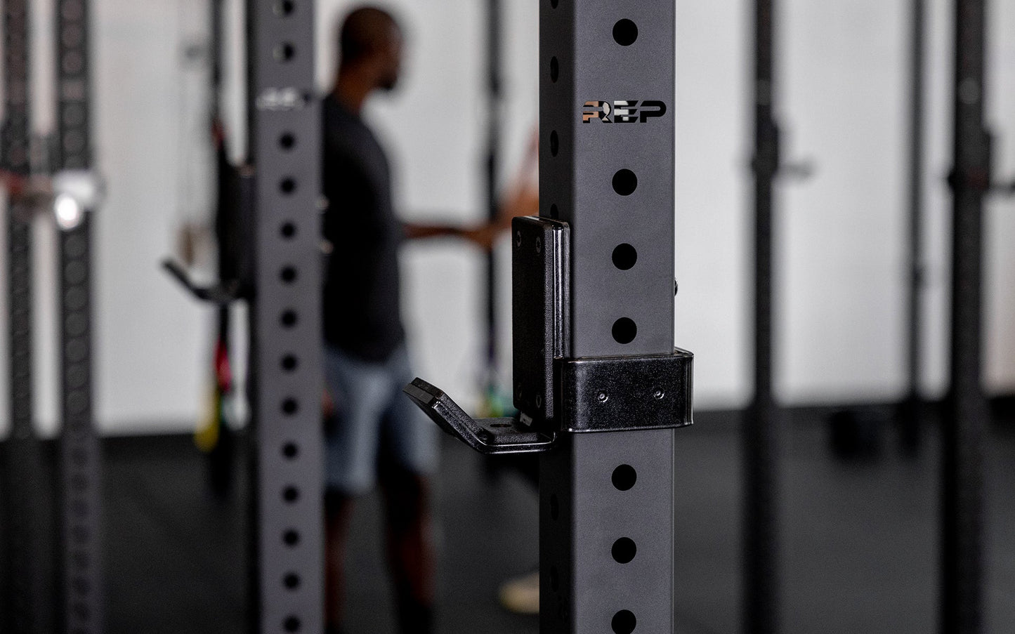 close-up side view of standard J-Cups 2.0 – heavy-duty barbell holder for PR-5000 power rack; 3x3” 11-gauge steel with metallic black powder coat, soft plastic lining, recessed hardware, and 1,000 lb capacity for safe, scratch-free, and stable lifting mounted on matte black power rack upright  from Rep Fitness UK | Shop Premium Gym Equipment for Home & Commercial Use, Best Online Gym Equipment UK