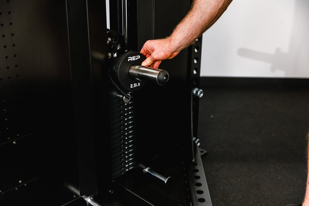 close up of man adjusting selectorized weight setting on Adonis™ Cable Tower plate loaded, Selectorized with base support, premium space-saving cable machine for home or commercial gyms, 1:1 and 2:1 pulley ratios, 34 cable positions, and compatibility with REP’s 5000 Series racks, Pegasus™ attachment, and Modular Storage System for unmatched versatility and performance from Rep Fitness UK | Shop Premium Gym Equipment for Home & Commercial Use, Best Online Gym Equipment UK
