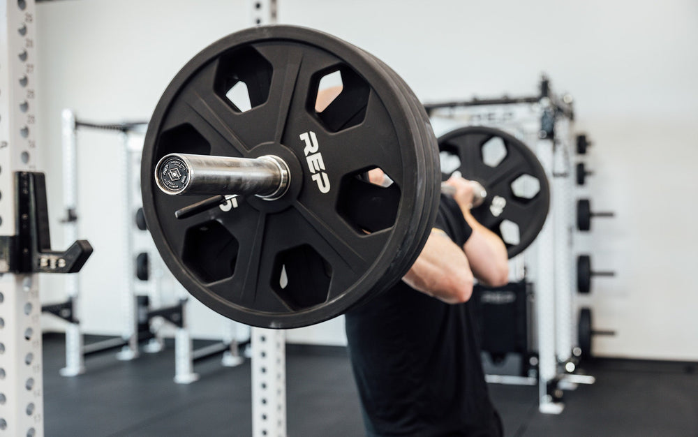 closeup of man using REP Fully Stainless Steel Double Black Diamond Power Bar, elite 20kg powerlifting barbell with ultra-aggressive mountain knurling, 29mm stiff shaft, bronze bushings, and IPF-standard specs, built for maximum grip and durability; available in stainless steel or Cerakote finishes for premium performance and corrosion resistance from Rep Fitness UK | Shop Premium Gym Equipment for Home & Commercial Use, Best UK Gym Equipment Online