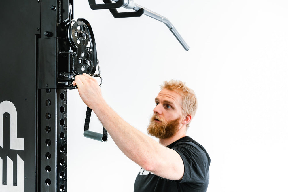 man adjusting Adonis™ Cable Tower plate loaded, Selectorized with base support, premium space-saving cable machine for home or commercial gyms, 1:1 and 2:1 pulley ratios, 34 cable positions, and compatibility with REP’s 5000 Series racks, Pegasus™ attachment, and Modular Storage System for unmatched versatility and performance from Rep Fitness UK | Shop Premium Gym Equipment for Home & Commercial Use, Best Online Gym Equipment UK
