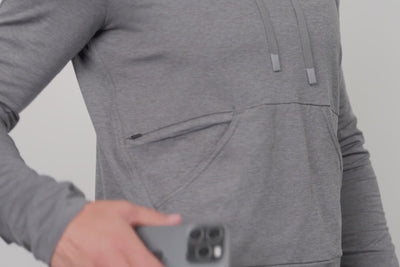 A video of an athlete zipper their phone in the pocket of the Women's Vellus Hoodie